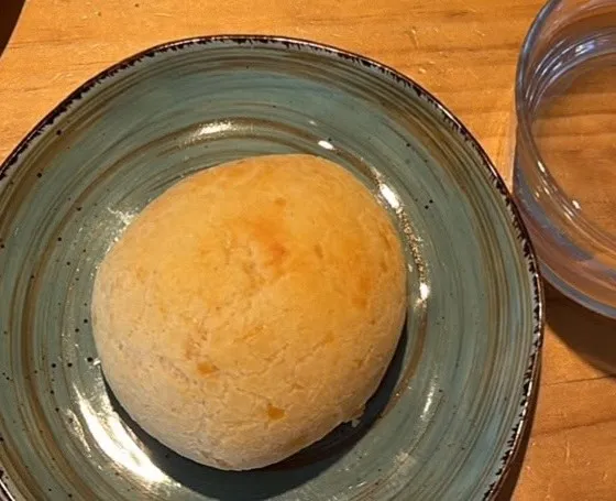 Pan de queso dorado en un plato turquesa sobre una mesa de madera